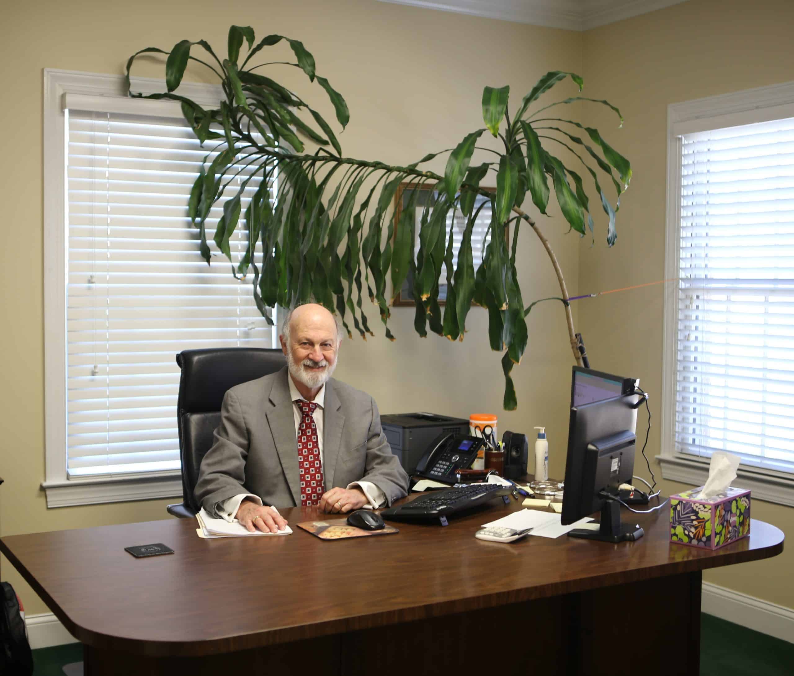 Charles Wynn of Charles M. Wynn Law Offices, PA sitting at his office desk smiling