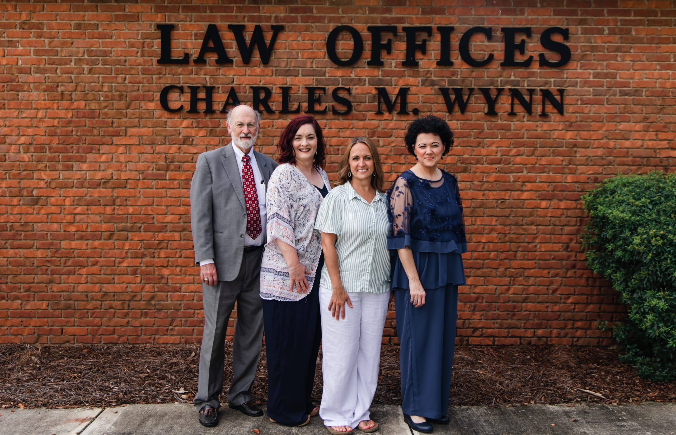 Charles Wynn and team of Charles M. Wynn Law Offices, PA standing outside the main office smiling